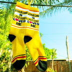 Close-up of yellow 'Someone in California Loves Me' socks hanging on a clothesline outdoors. [lf]