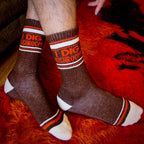 Lifestyle shot of 'I Dig Mushrooms' socks on a person's legs against a red fuzzy background.