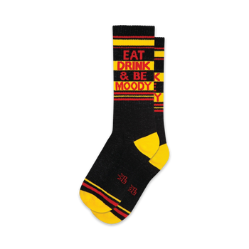 black socks with yellow toes, heels, and cuffs. red and white striped legs. 'eat drink & be moody' in red and yellow letters on the front. crew length, for men and women.  / 