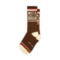Pair of brown crew socks with off-white and red stripes. Text reads 'NOT A MORNING PERSON' in a retro font.