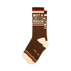 Pair of brown crew socks with off-white and red stripes. Text reads 'NOT A MORNING PERSON' in a retro font.