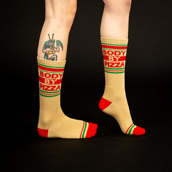 Lifestyle shot showing 'Body By Pizza' socks on a person's legs against a black background. [lf]