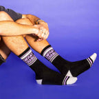 Close-up shot of a person sitting with their legs crossed showing off the Enfant Terrible socks [lf]