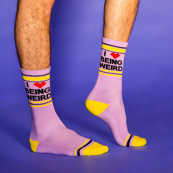 [lf] Lifestyle shot of a person's legs wearing the 'I Love Being Weird' socks against a purple background.