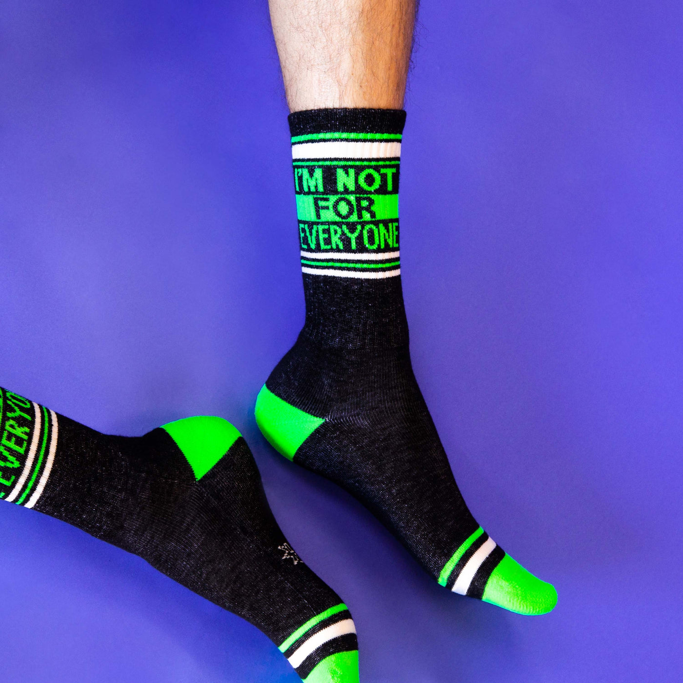 Lifestyle shot of a person wearing the 'I'm not for everyone' socks on a purple background. [lf]