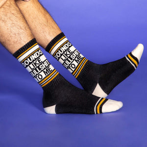 A pair of black socks with white and yellow stripes at the top and white toes and heels. The socks have the words 