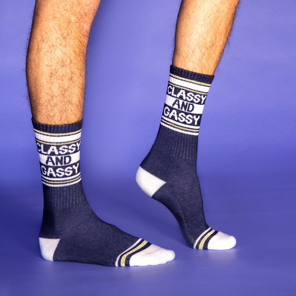 Lifestyle shot showing the socks on a person's feet. The socks are navy blue with a white and gold stripe design. [lf]