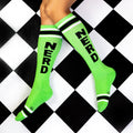 Lifestyle shot of a person wearing the lime green 'Nerd' socks on a black and white checkered floor. [lf]