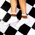 Flat lay: Two white 'Farts' socks on a black and white checkered floor. [lf]