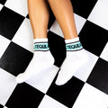 Lifestyle shot of a person's legs wearing the Tequila socks on a black and white checkered floor. [lf]