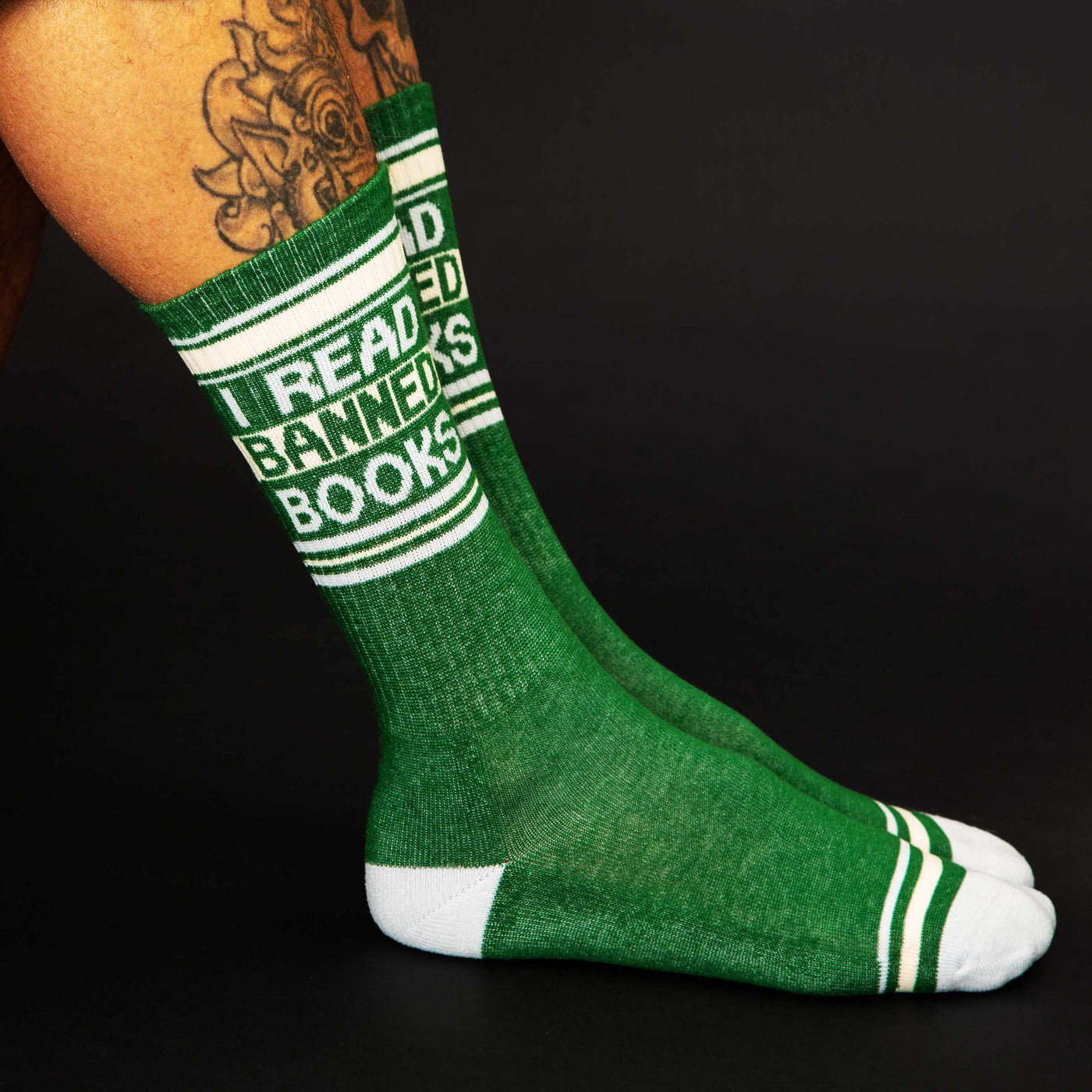 Lifestyle shot showing the 'I Read Banned Books' socks on a person's legs against a black background. [lf]