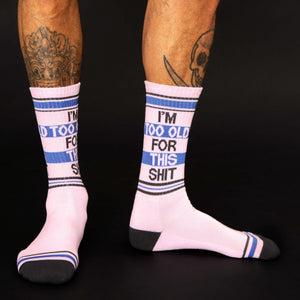 A pair of pink socks with black toes, heels, and lettering. The lettering on the socks reads 