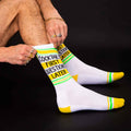 Close-up shot of a man putting on the 'Cocktails First Questions Later' socks. [lf]
