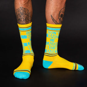 A pair of yellow socks with blue toes, heels, and lettering. The lettering on the left sock reads 