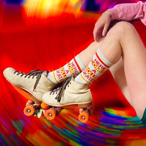 A young person is wearing white roller-skates and socks with the text 