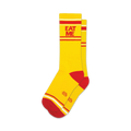 A pair of yellow crew socks with red and white stripes and the words 'EAT ME' in red.  Small logo on the sole.