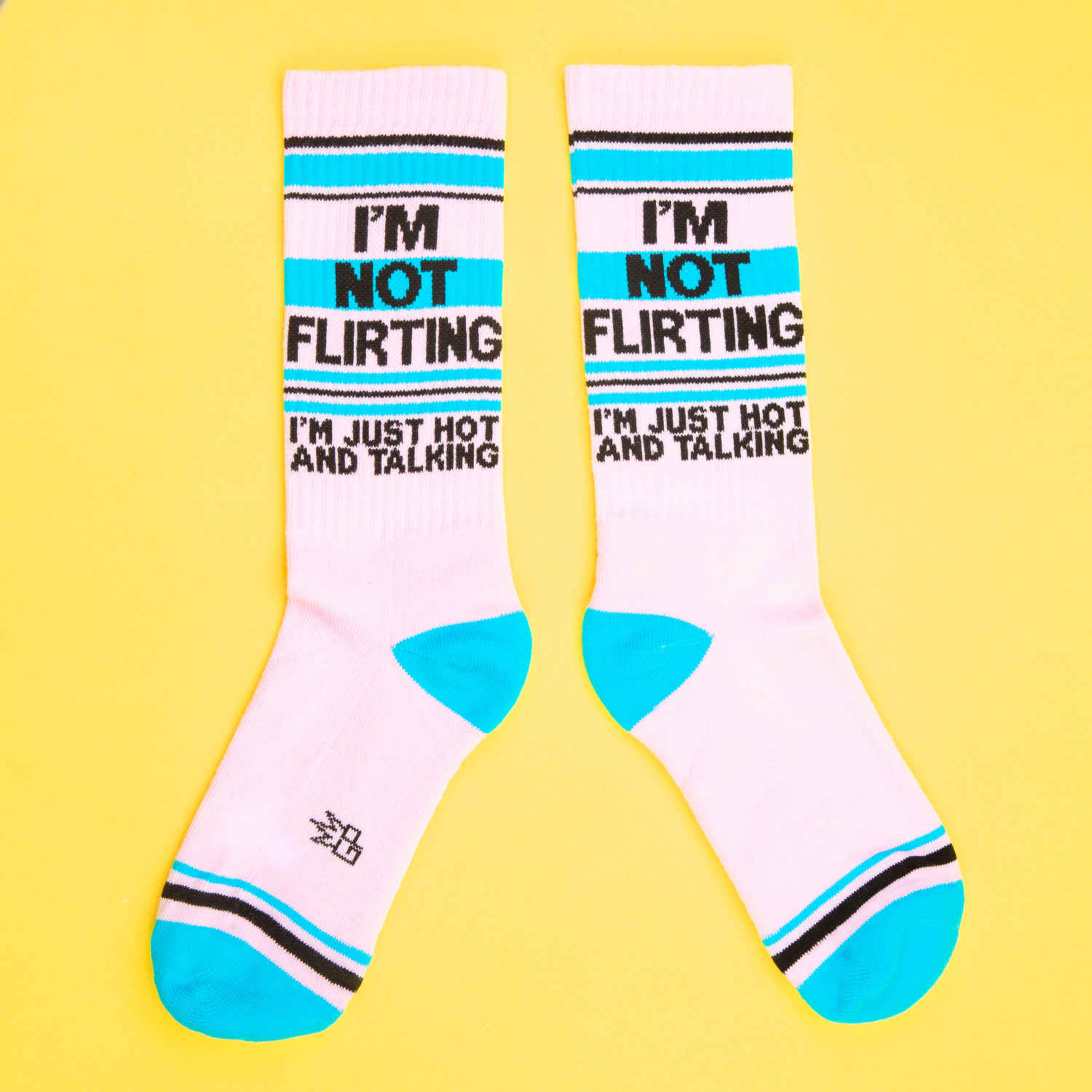 Two 'I'm Not Flirting' socks laid flat, showing the full design. They are pink, teal and black.