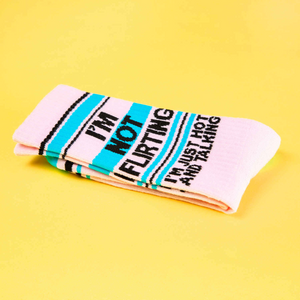 A folded pair of 'I'm Not Flirting' socks on a yellow background, showcasing the fabric and design.