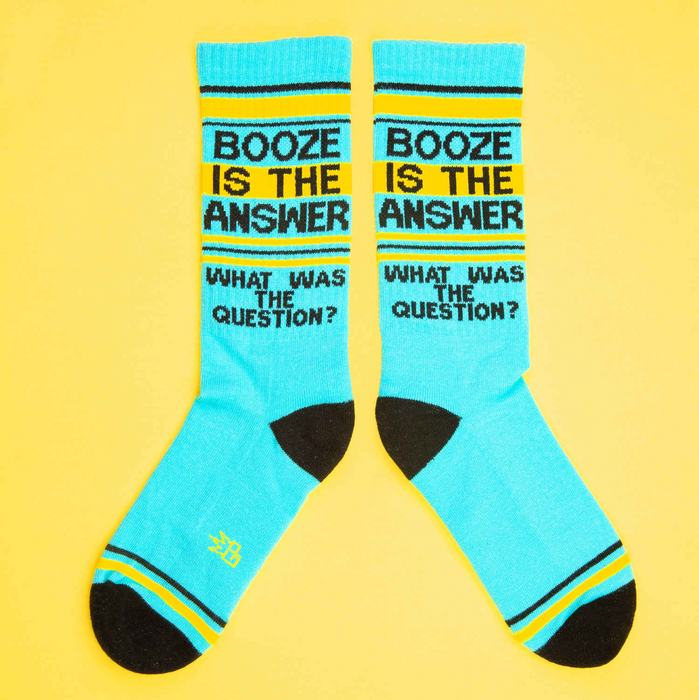 Flat lay of two 'Booze Is The Answer' socks on a yellow background.