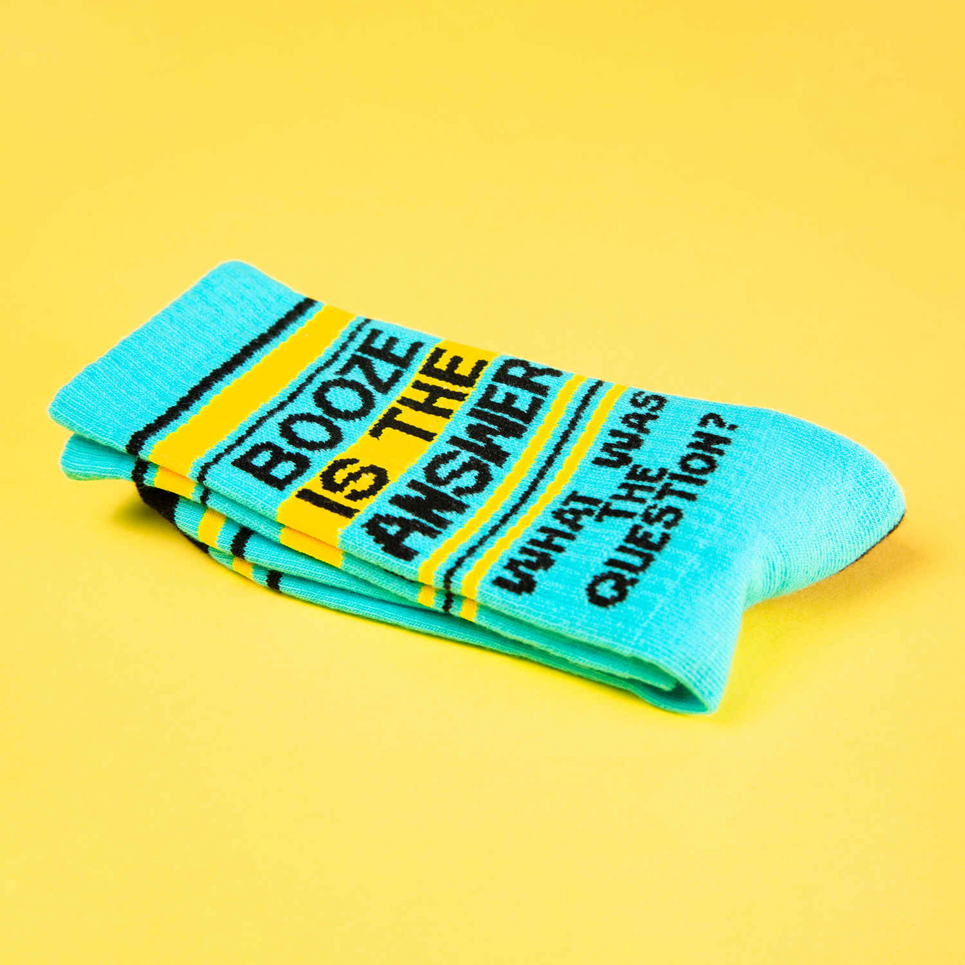 Folded light blue 'Booze Is The Answer' sock on yellow background.