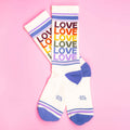 Pair of 'Love' rainbow socks on pink background. [lf]