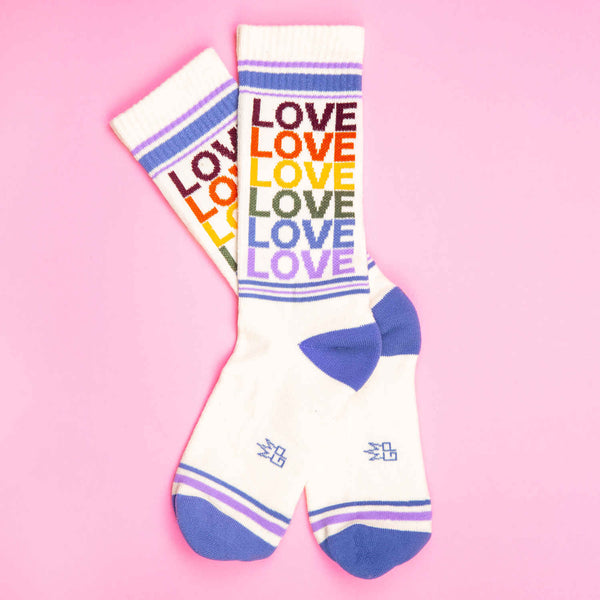Pair of 'Love' rainbow socks on pink background. [lf]