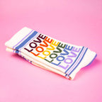 Folded pair of 'Love' rainbow socks on pink background. [lf]