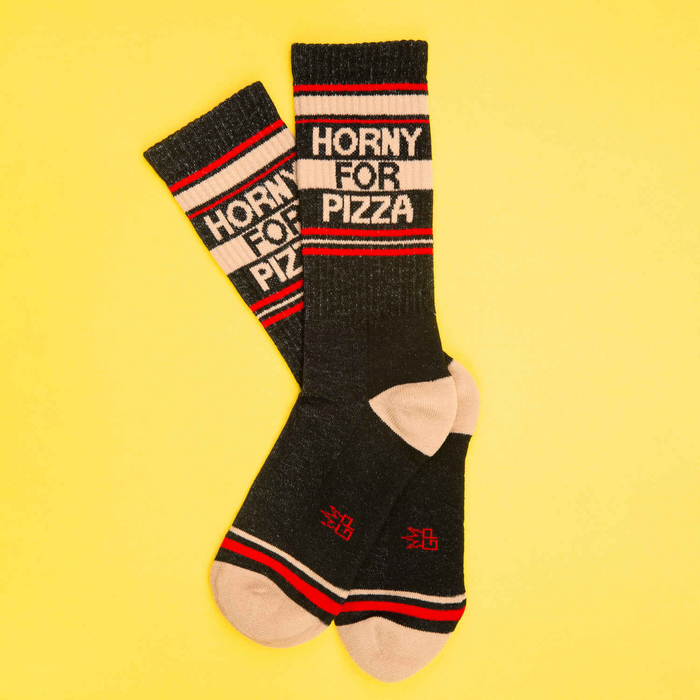 Flat lay of 'Horny for Pizza' socks on a yellow background.