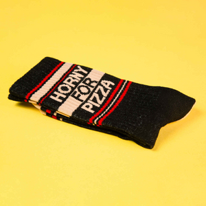 Folded 'Horny for Pizza' socks on a yellow background.