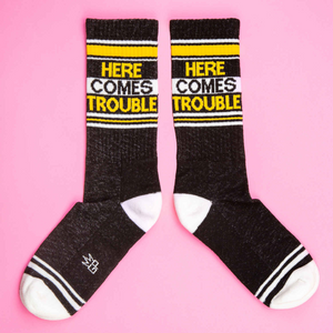 A pair of black socks with white toes, heels, and cuffs. The socks have two wide yellow stripes around the leg and the words 