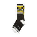 Pair of black crew socks with yellow and white stripes and the text 'HERE COMES TROUBLE' in yellow.