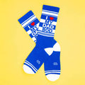Flatlay of a pair of blue and white striped 'I love my dad bod' crew socks against a yellow background.