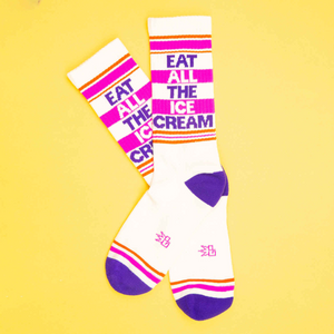 Flat lay of two 'Eat All The Ice Cream' socks on a yellow background.