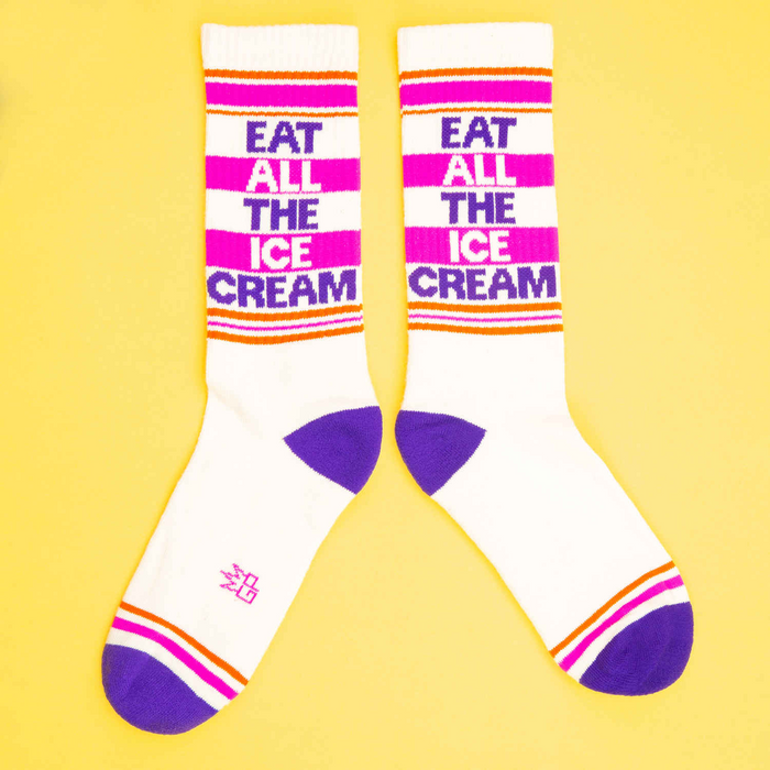Another flat lay showing two 'Eat All The Ice Cream' socks, arranged differently on a yellow background.