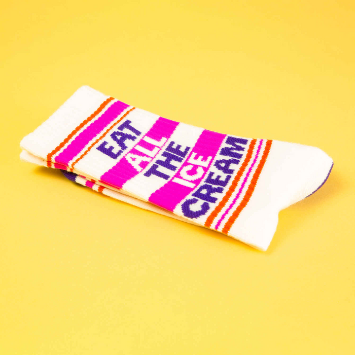 Close-up view of folded 'Eat All The Ice Cream' socks on a yellow background, highlighting the sock's design and texture.