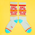 Two 'Don't Let The Bullshit Get You Down' socks laid flat on a yellow background, showcasing both sides of the design. [lf]