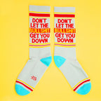 Two 'Don't Let The Bullshit Get You Down' socks laid flat on a yellow background, showcasing both sides of the design. [lf]