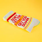 Close-up of a single 'Don't Let The Bullshit Get You Down' sock folded on a yellow background, highlighting the design details. [lf]