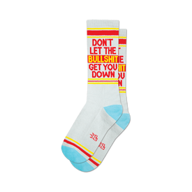 a pair of white socks with the words 'don't let the bullshit get you down' on the leg in red and yellow letters. the heel and toe are red and the top is blue with two yellow stripes.