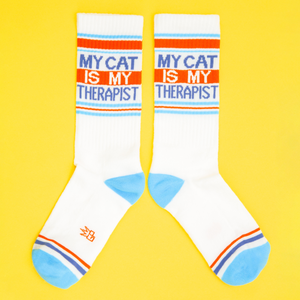 Flatlay photo of 'My Cat Is My Therapist' socks on a yellow background.