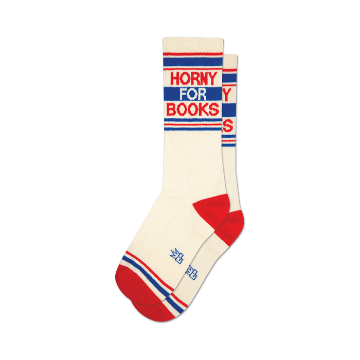 a pair of socks with the words 'horny for books' on them. socks that are white with red and blue stripes at the top and red heels and toes. }}