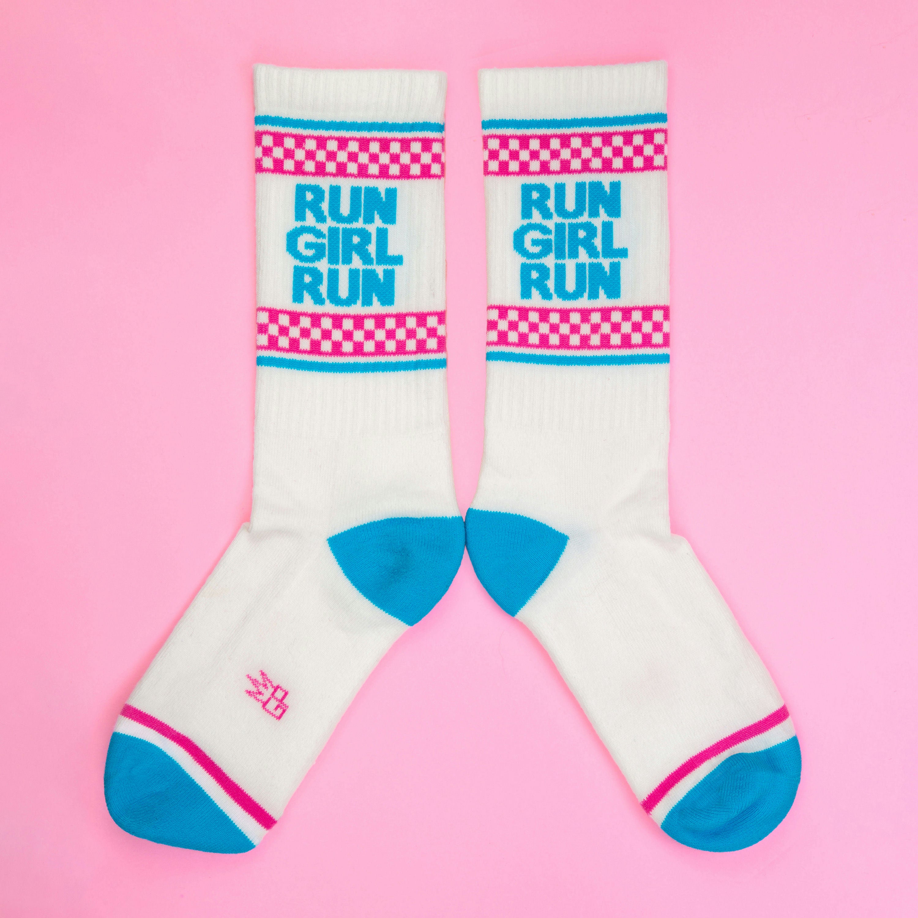 Another flatlay of 'Run Girl Run' socks on pink; socks are arranged to showcase the design better. [lf]