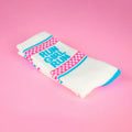Close-up of folded 'Run Girl Run' socks on pink background. Highlights the sock's texture and design details. [lf]
