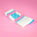 Close-up of folded 'Run Girl Run' socks on pink background. Highlights the sock's texture and design details. [lf]