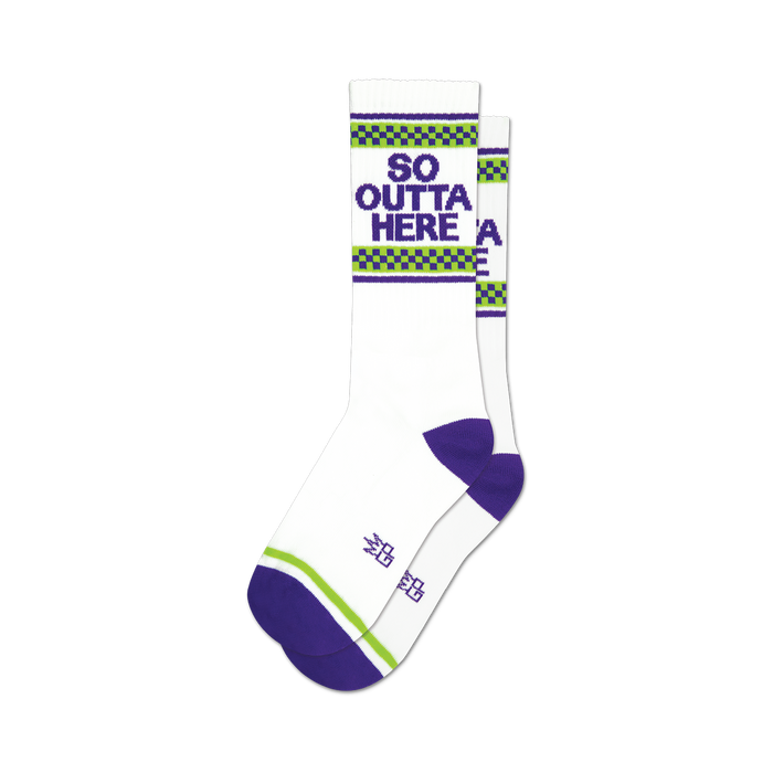 socks that are white with purple toes, heels, and cuffs. there is a green and white checkered pattern above the purple cuff. the words 'so outta here' are printed in purple block letters on the front of the socks. }}