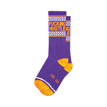socks that are purple with orange toes, heels, and the word 'hustle' in large letters up the side of the leg. the word 'fucking' is more subtly woven into the fabric and is only visible upon close inspection.