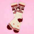 Flat lay of 'See You In Hell' socks on a pink background. [lf]