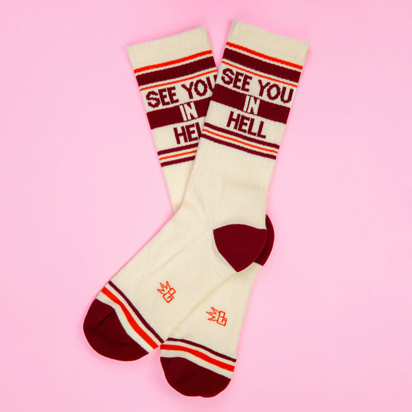 Flat lay of 'See You In Hell' socks on a pink background. [lf]