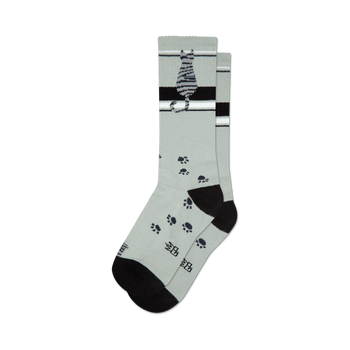 socks that are gray with a pattern of black cat paw prints. there is a black heel and toe with a gray toe seam. the top of the foot has a black band with two white stripes. the leg of the sock has a black cat sitting with its tail wrapped around its paws. the cat is gray with black stripes.