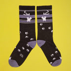 Lifestyle shot showcasing the black crew socks with upside-down white cat and paw print design. [lf]